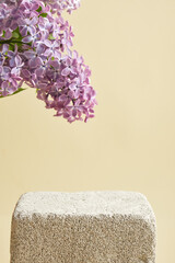 lilac branch and aerated concrete podium on a beige background, mock-up background for product presentation
