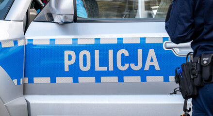 Blue Polish police vehicle and a policeman, policja, police car side detail, closeup. Polish...