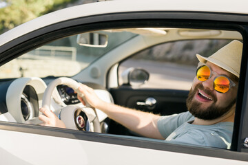Happy man sitting in white convertible car with beautiful view and having fun - travel summer...