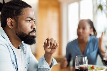 Close up of young African American man feeling sad while arguing with his wife at dining table