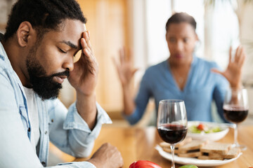 Close up of young African American man feeling sad while arguing with his wife at dining table