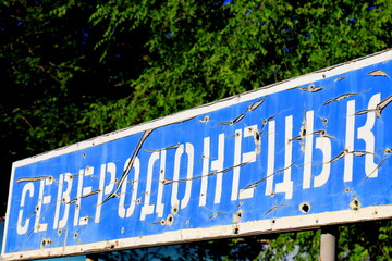 Russia war against Ukraine, Ukrainian war. Road sign, inscription in Ukrainian - Severodonetsk, pierced by bullets, Destruction in Ukraine