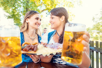 Two girls in Tracht with food and drink in beer garden