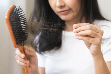 Wall murals Beauty salon Serious asian young woman holding brush holding comb, hairbrush with fall black hair from scalp after brushing, looking on hand worry about balding. Health care, beauty treatment, hair loss problem.