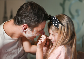 Father and daughter soil each other with flour