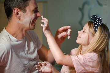 Father and daughter soil each other with flour