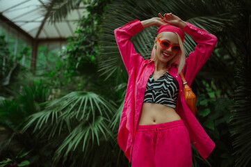 Fashionable happy smiling woman wearing trendy orange sunglasses, pink fuchsia color bandana, linen...
