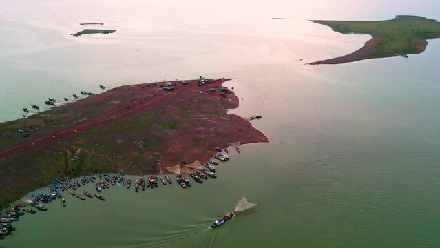 Aerial view of Ben Nom fishing village, a brilliant, fresh, green image of the green algae season on Tri An lake, with many traditional fishing boats anchored.