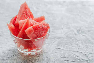 slices of sweet juicy watermelon in a glass bowl on a light surface close up