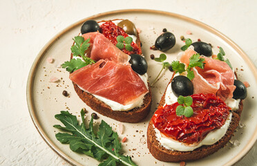 sandwiches with cheese and prosciutto, dried tomatoes and olives, breakfast on a plate,