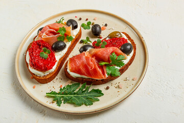 sandwiches with cheese and prosciutto, dried tomatoes and olives, breakfast on a plate,