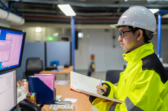 Inside the large Industry Factory Female Computer Engineer Works on Personal Computer She coding program for control machine,Thailand people work on fours monitors,Programmer working with serious