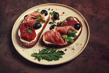sandwiches with cheese and prosciutto, dried tomatoes and olives, breakfast on a plate,
