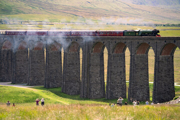 The Flying Scotsman steam train locomotive crosses The Ribblehead Viaduct as crowds of tourists spectate. - 621580327
