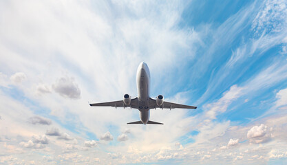 Fototapeta na wymiar White passenger airplane flying in the sky amazing clouds in the background - Travel by air transport