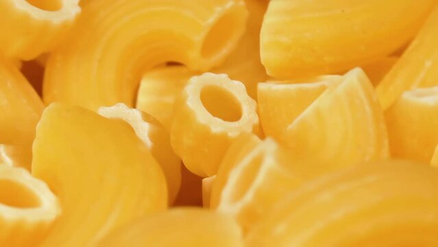 Uncooked Chifferi Rigati Pasta Rotating - Macro. Fat and Unhealthy Food - Close-Up. Classic Dry Macaroni. Italian Culture and Cuisine. Raw Golden Pasta