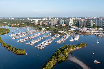 Aerial view of Dinner Key Marina and City of Miami City Hall with Coconut Grove, Miami skyline in background on calm sunny clear summer morning.