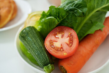 A plate of mixed vegetables is placed on the table. There are sliced tomatoes and cucumbers to prepare for a holiday dinner. in the kitchen