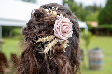 Beautiful brunette hair tresses bride with hairstyle and rose hair decoration plus strands of wheat ears standing outdoor back view behind in wedding day