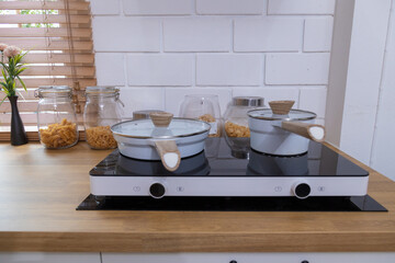 Various kitchen utensils set of cooking pots, pans, knives, cups, bowls, condiments on a wooden background.
