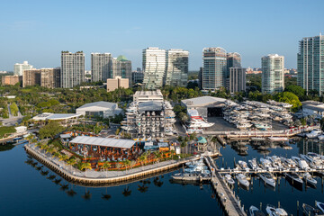 Fototapeta premium Aerial view of waterfront bars, restaurants and marina in Coconut Grove, Miami, Florida with skyline in background on calm clear sunny summer morning.