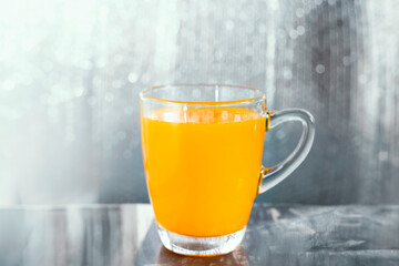 Glass of orange juice, shiny silver background