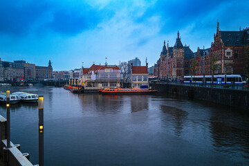 Amsterdam City Skyline, marina at Open Havenfront Canal, and Central Station in rain at twilight in the Netherlands