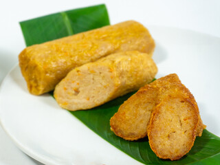 Concept photo of kekian,hekeng or ngohiong food made from minced meat wrapped in steamed bean curd skin served with sauce on the kitchen table.Some materials,bamboo steamer, white wall as background. 