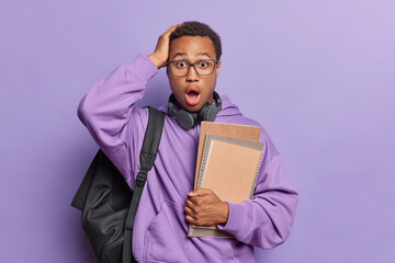 Horizontal shot of scared emotive African guy with short curly hair and beard carries black...