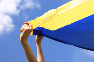 Yellow and blue flag of Ukraine in the woman's hands. Fluttering blue and yellow flag of Ukraine...