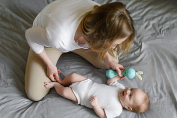 Happy mom and baby are playing with a rattle.Toy for the development of fine motor skills of the baby.Children's Day