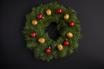 Christmas decor. Christmas ring or wreath with red bead  and gold nut on the black  background. Top view.