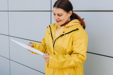 Young woman in yellow uniform holding package. Delivery service holding to sent a white package...