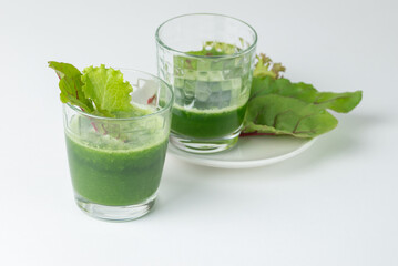 Two glasses with freshly squeezed juice or smoothie with fresh  chard leaves on on a white background with copy space