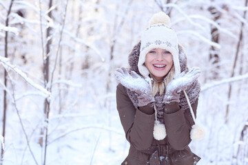 Happy blonde girl in a winter scenery with a hat and gloves.
