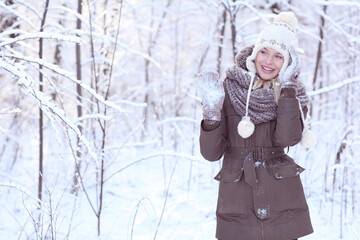 Happy blonde girl in a winter scenery with a hat and gloves.