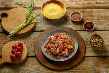 Israeli couscous with sumac and chicken stew pieces on the table in a plate next to spices and vegetables.