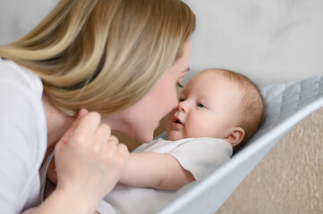 A happy child lies in a children's deck chair,smiles and is happy to see mom,mom talks to the baby. Childhood,motherhood