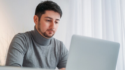 Focused worker. Computer research. Concentrated employee. Serious business man studying information completing task at laptop at light office workplace.