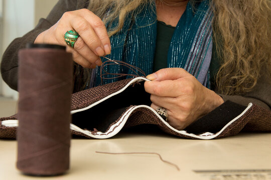 M&atilde;os costurando z&iacute;per em tecido jeans com linha e agulha. Corte e costura customizando roupas descartadas da ind&uacute;stria t&ecirc;xtil de S&atilde;o Paulo, Brasil.    