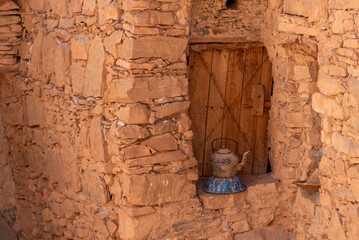 An old tea can in front of an antique window shutter of a berber house