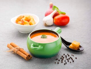 Tomato soup with ingredients around on a slate background with bread croutons 