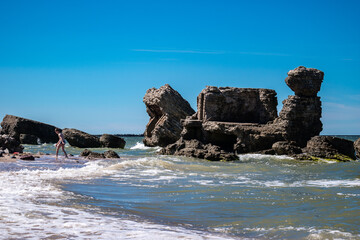 Liepaja, Latvia - June 29, 2023: kids enjoying summer and having fun in the sea. War ruins near Karosta in the Baltic Sea.