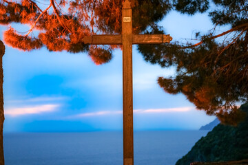 Religious crucifix under tree on coastal hillside
