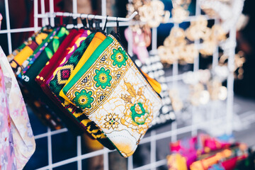 Closeup of multi-colored patterned purses on a rack of product display. Selective focus. 