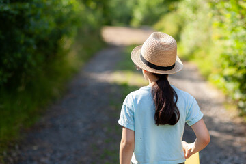 Young woman wearing a straw hat in the park. Back view.