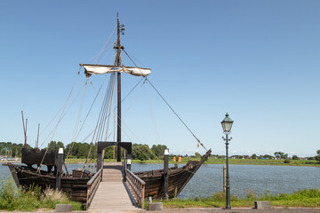 Replica of an old merchant ship -Kamper Kogge,  along the river IJssel near the Dutch historic Hanseatic city of Kampen in Overijssel. - obrazy, fototapety, plakaty