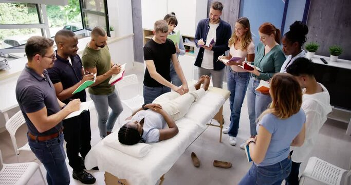 Male Instructor Teaching Massage Technique To Group