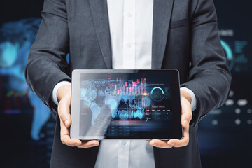 Close up of businessman hands holding tablet with creative global forex chart on dark background. Concept of stock market and financial success.