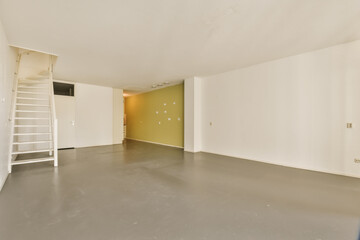 an empty room with ladders on the wall and stairs leading up to another room in the floor is grey